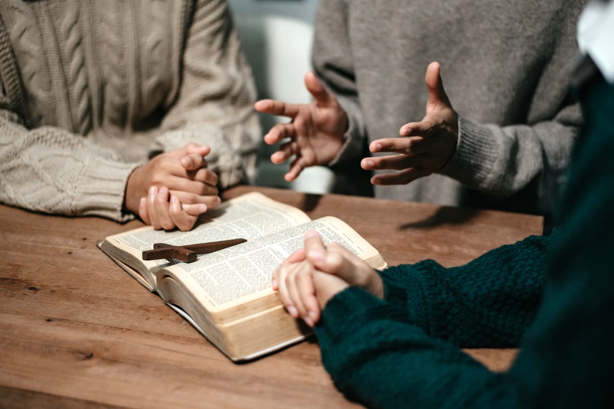 A group of men gathered around a bible on a table.